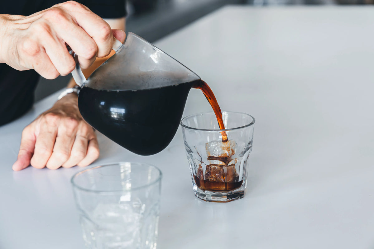 サーバーからグラスにコーヒーを注ぐ手元