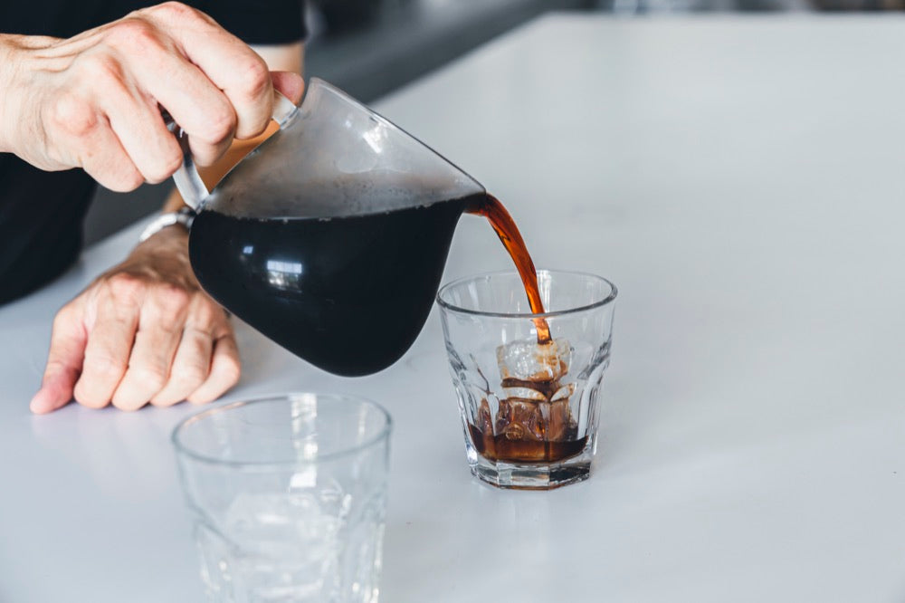 氷入りのグラスにコーヒーを注ぐ手元
